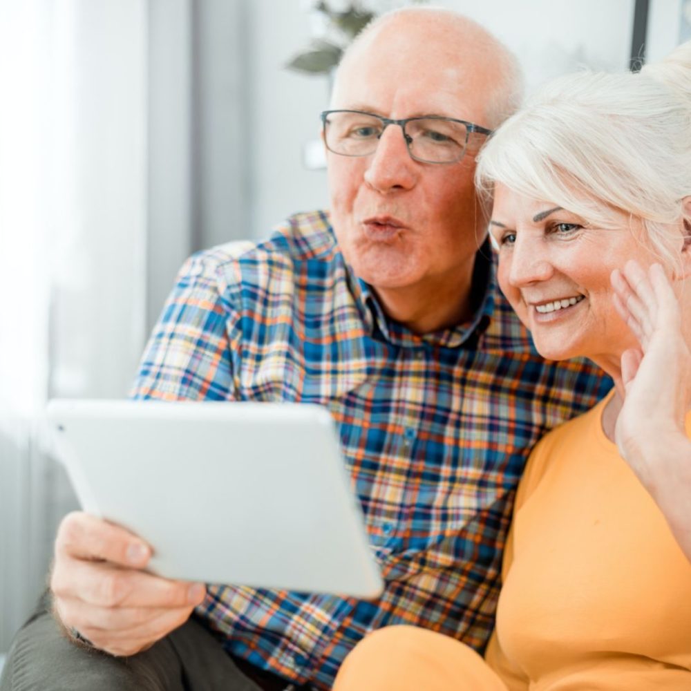 Happy senior couple video chatting using tablet at home